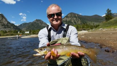 Guided fly fishing customer holding brown trout